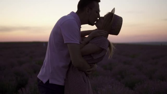 一对年轻的情侣在盛开的薰衣草地里亲吻，慢镜头