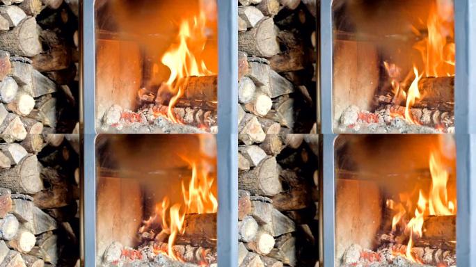 白天在耐火玻璃后面的自制现代炉灶中燃烧柴火的特写镜头，旁边是一大堆柴火。环保能源