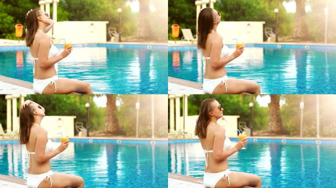 喝橙汁的女人在游泳池附近放松。