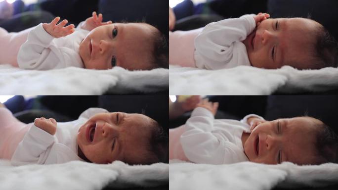 刚出生的女婴哭泣，而无法识别的人正在换尿布，躺在床上