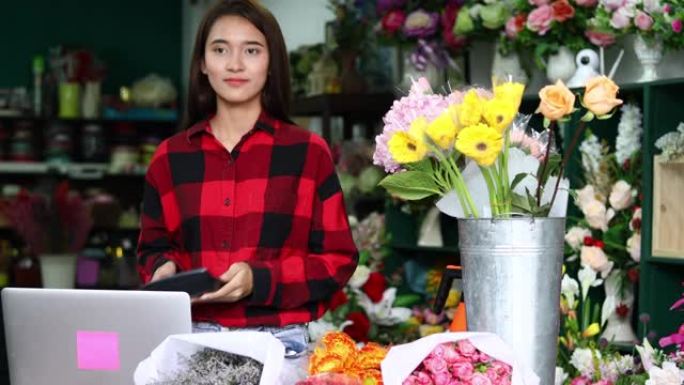 亚洲女花店小商花店老板，她正在用电话和笔记本电脑为她的商店下订单。