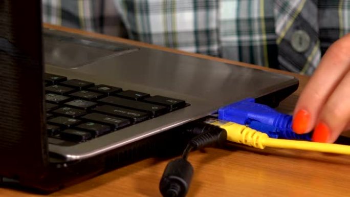 女性手从桌子上的笔记本电脑上断开usb、vga和局域网电缆