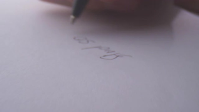 笔在纸上写一封信的特写镜头。纸上的文字笔迹