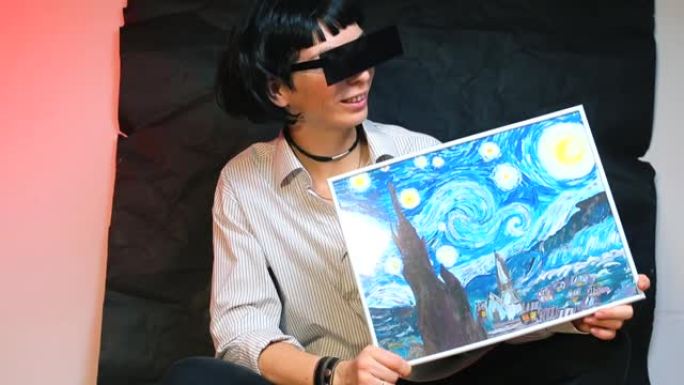 戴长方形眼镜的女孩拿着一幅名画的复制品。
