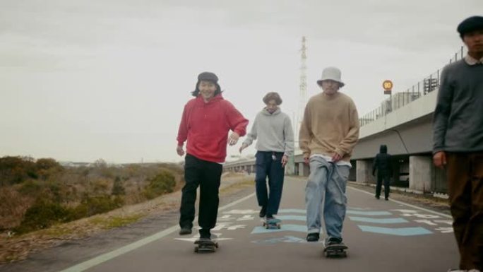 年轻男性日本滑板运动员骑在公路上