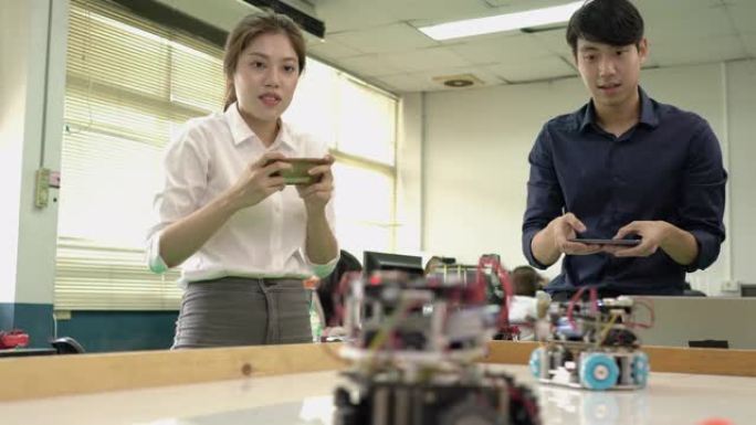 亚洲工程师学生在现代实验室中指挥控制操纵杆和测试机器人技术。机器人概念、技术发展和协作管理。
