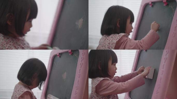 蹒跚学步的女孩在家里的黑板上画画