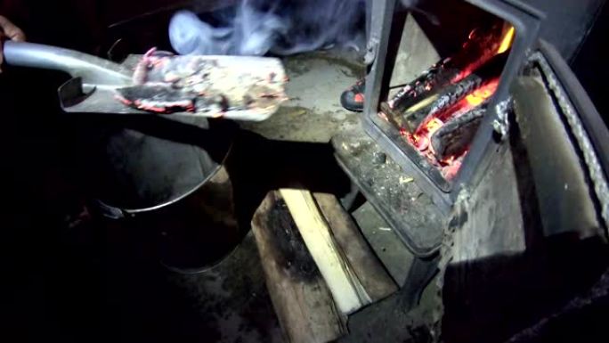 将燃烧的木炭从壁炉铲到桶中