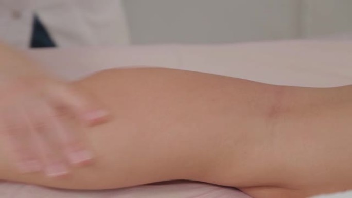女性按摩治疗师对年轻女孩的小腿肌肉进行按摩
