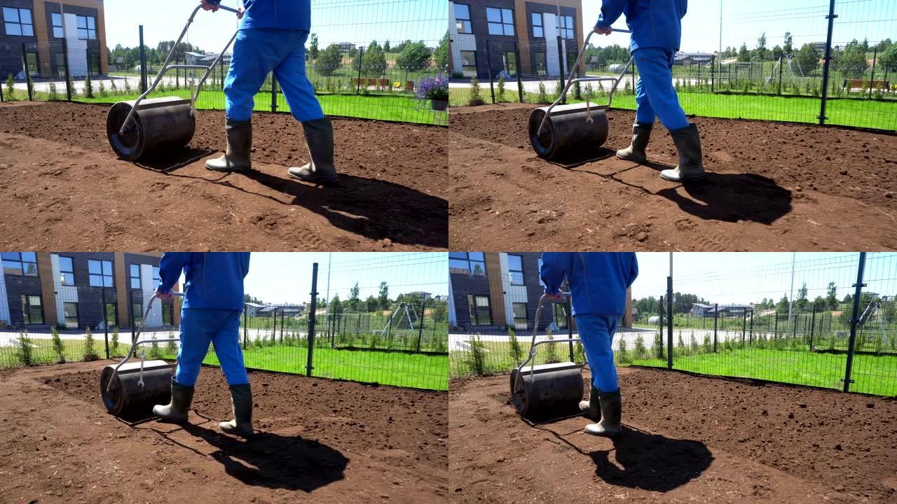 在播种草坪之前，人类正在用滚筒准备土壤。手持