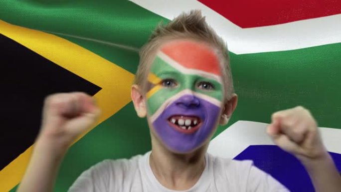 南非国旗背景上的快乐粉丝。有着民族色彩的脸的快乐男孩。