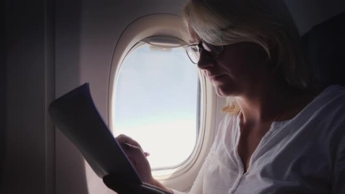 一名戴着眼镜的年轻女子在飞行中阅读商业文件