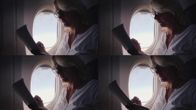 一名戴着眼镜的年轻女子在飞行中阅读商业文件