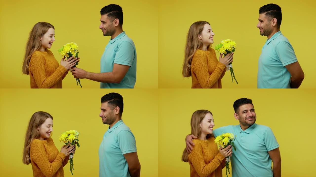 年轻的黑发男人给美丽的姜黄色女孩送花，祝生日快乐，祝贺，可爱的夫妇拥抱