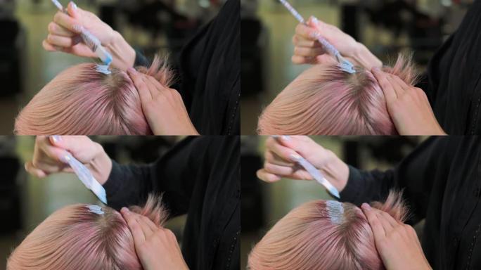美发师调色师在女客户的头发上涂上油漆。