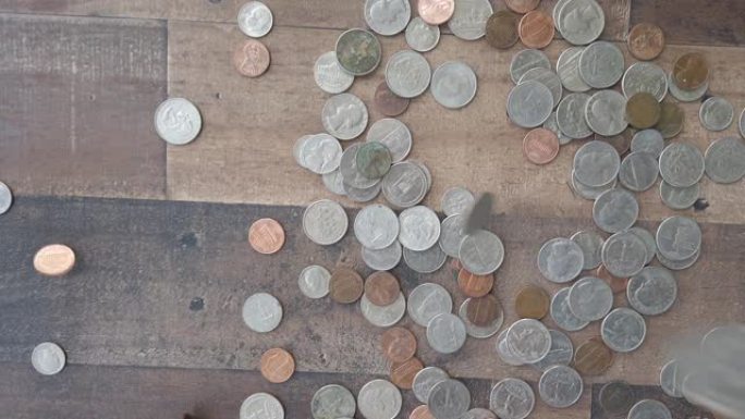 许多硬币落在木地板上慢动作，酷钱概念4k平放。