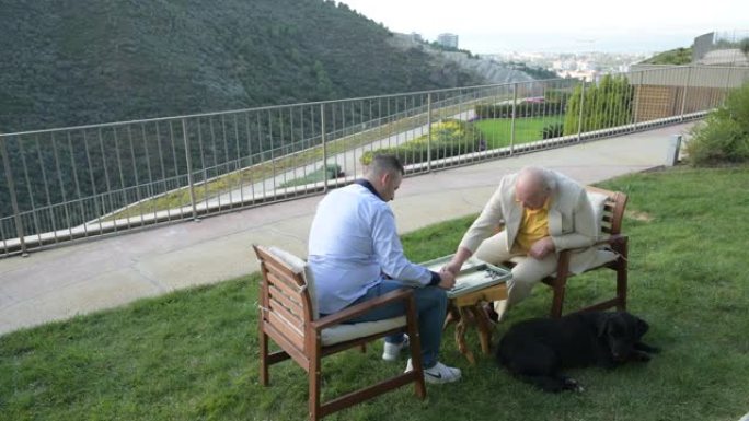 祖父和他的儿子正在花园里玩双陆棋