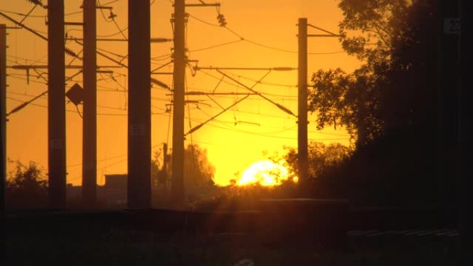 剪影中的日落铁路平交道口。电气化铁路。太阳在地平线上。工作日结束。火车撞车或灾难的危险路段