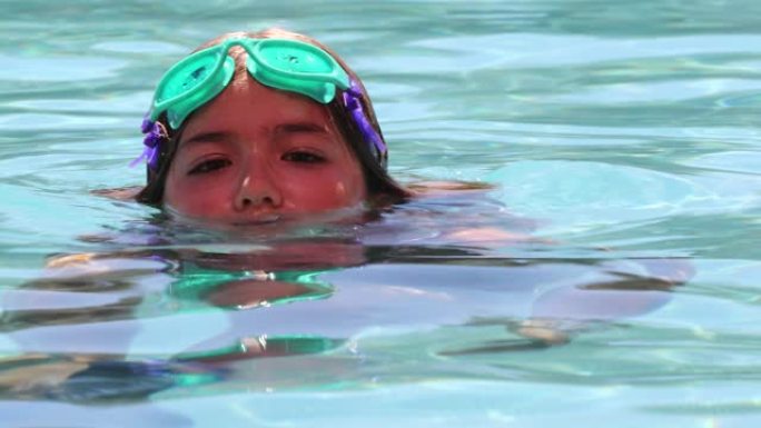 小女孩享受游泳池水在水面屏住呼吸