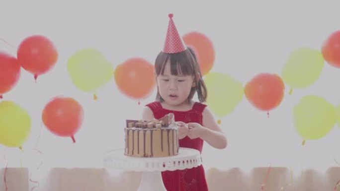 蹒跚学步的女孩在生日派对上准备切生日蛋糕
