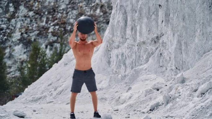 集中肌肉的人在山里用黑球锻炼。