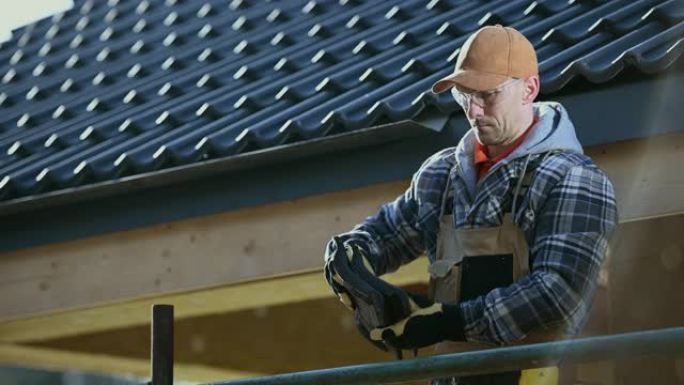 30多岁的工人手里拿着陶瓷屋顶瓦片准备工作。