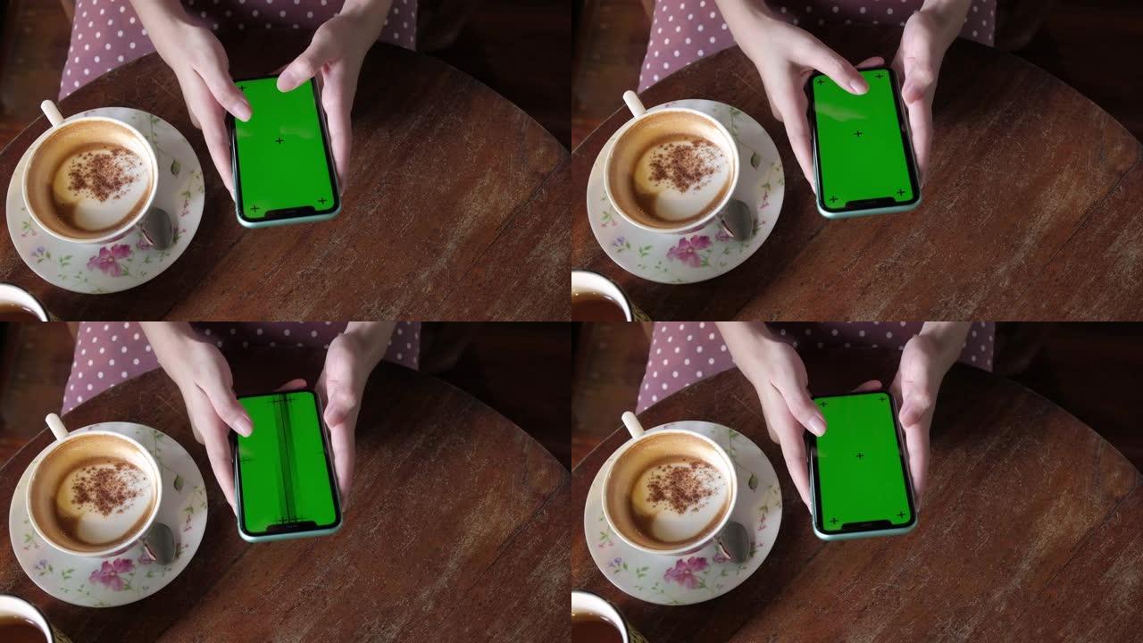 女人在咖啡休息时使用绿屏智能手机。