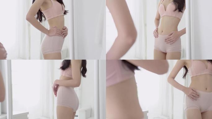 年轻的亚洲女性穿着内衣照镜子的生活方式，腹部身材苗条，穿着内衣的美女身材适合减肥，腹部和腰部性感完美