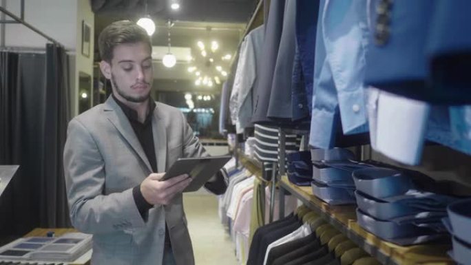 男装商店经理在数字平板电脑上检查库存 (慢动作)