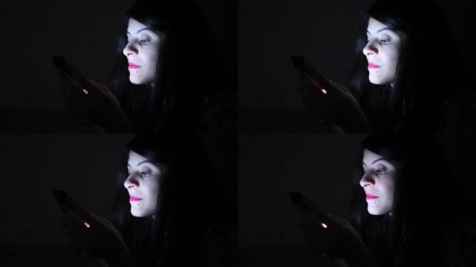 女人独自在黑暗中晚上使用智能手机设备