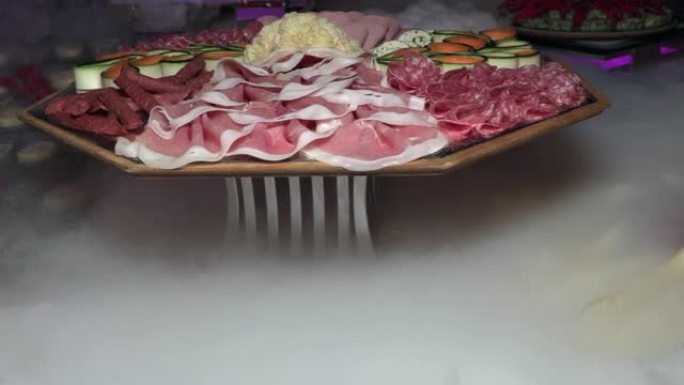 节日餐桌上的托盘上切成薄片的火腿和香肠