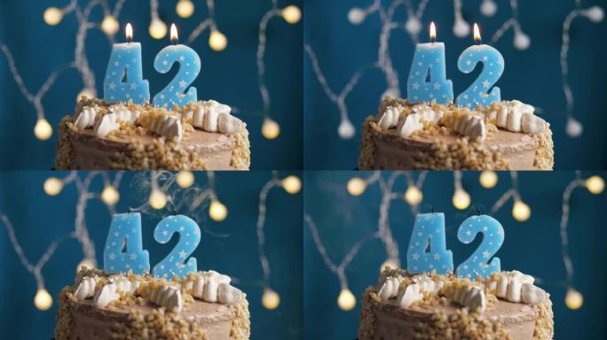 蓝色背景上有42号蜡烛的生日蛋糕。蜡烛吹灭了。慢动作和特写视图