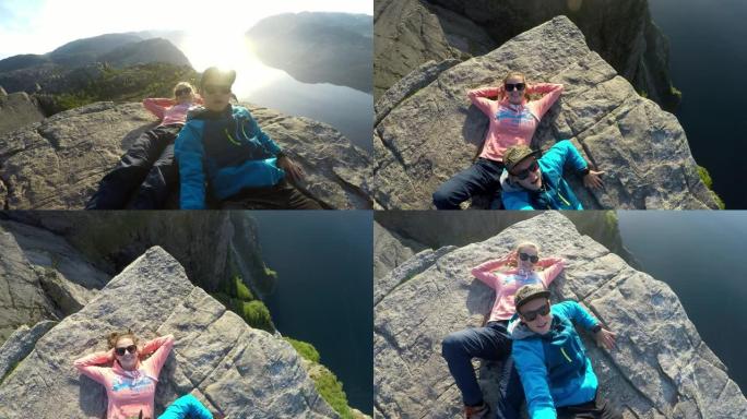 一对年轻夫妇躺在挪威Preikestolen (讲坛岩石) 的边缘，俯瞰Lysefjord。大自然中