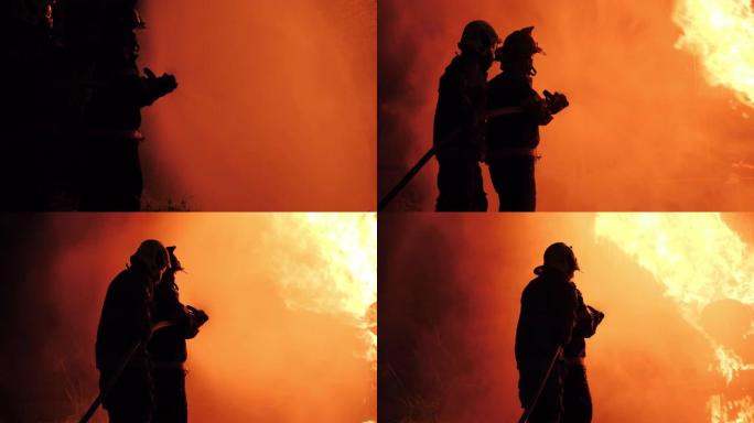 亚洲消防员穿防火服的后视图。消防员晚上在消防站喷水灭火。训练消防演习概念。
