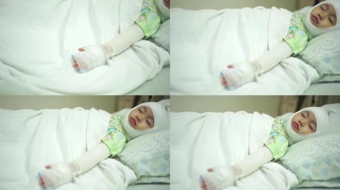 亚洲女婴躺在医院，头部和手臂被绷带包扎在床上。头部和手臂受伤的女婴。手持镜头，真实生活