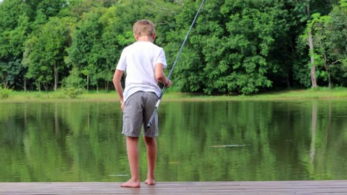 小男孩在户外自然的原始美丽的绿湖钓鱼
