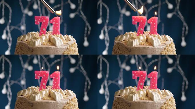 蓝色背景上有71号粉色蜡烛的生日蛋糕。蜡烛着火了。慢动作和特写视图