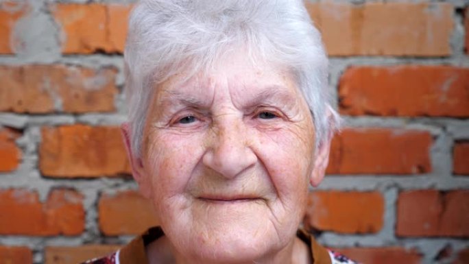 快乐的老妇人的肖像，白发看着镜头，微笑着。脸上有皱纹的老太太表现出开朗或快乐的情绪。奶奶的积极面部表