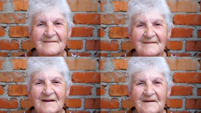 快乐的老妇人的肖像，白发看着镜头，微笑着。脸上有皱纹的老太太表现出开朗或快乐的情绪。奶奶的积极面部表