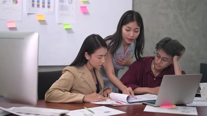 年轻的亚洲女性团队在办公室讨论工作后的行为是疲倦，不满意，无聊的工作