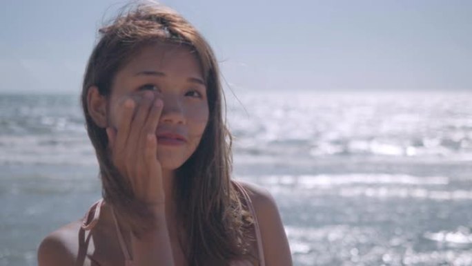 女人在海边海滩热带休息和放松旅行生活方式在比基尼上使用防晒保湿剂防紫外线乳液夏季概念