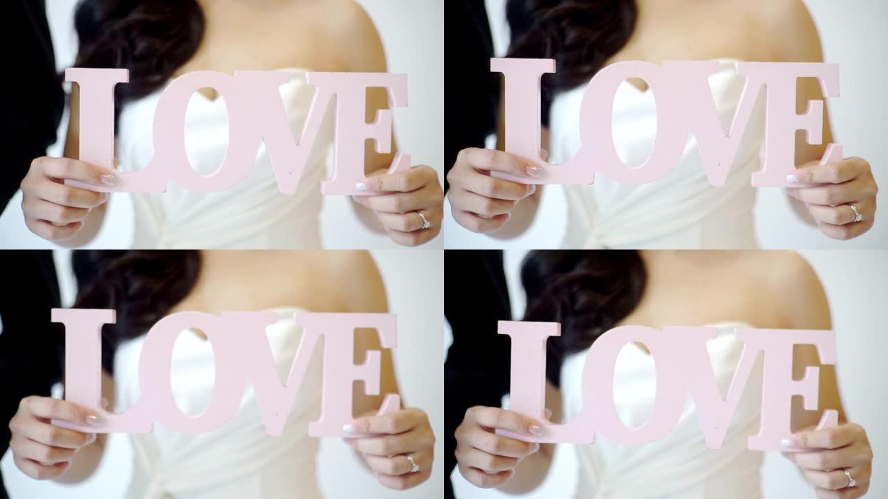 新娘举着白色背景上带有 “爱” 字样的牌子。