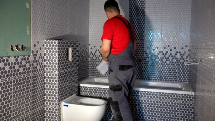 熟练工人在新的现代浴室中安装马桶冲水按钮