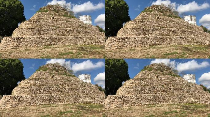 手持宽幅拍摄墨西哥一个村庄的玛雅神庙废墟，背景为白色棉花云