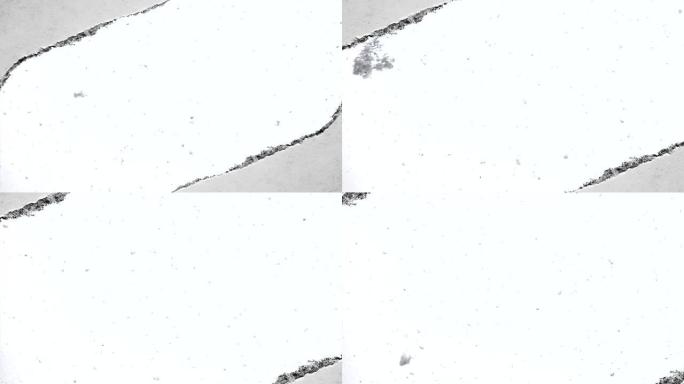 缓慢落下的雪的创意慢动作视频，可以通过旧复古垃圾老式纸边缘撕裂的孔看到。