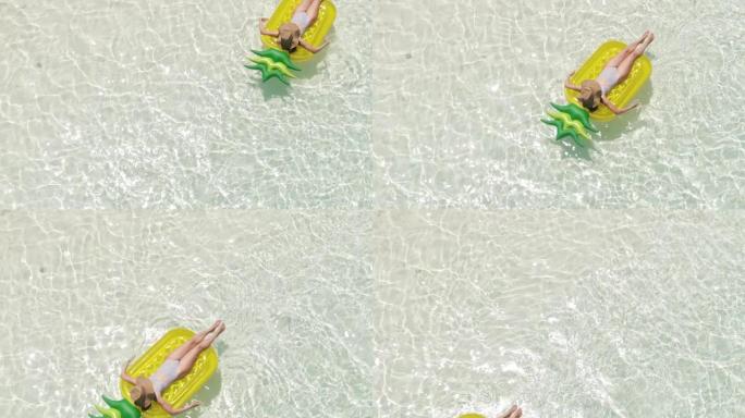 漂浮在水晶般清澈的水中的女孩的空中，在热带岛屿天堂的充气水果环上放松。文本复制的空间。