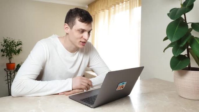 企业家英俊的年轻白人正在使用笔记本电脑进行在线视频通话。坐在家里说话和微笑