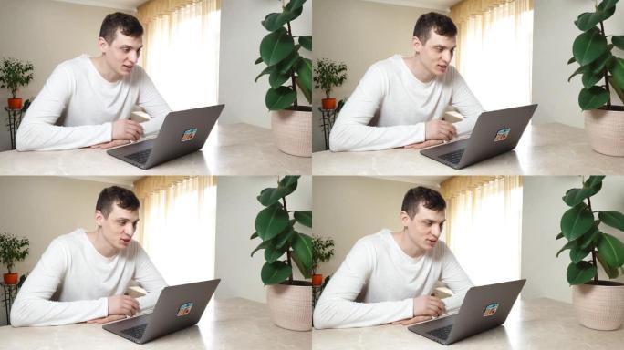 企业家英俊的年轻白人正在使用笔记本电脑进行在线视频通话。坐在家里说话和微笑