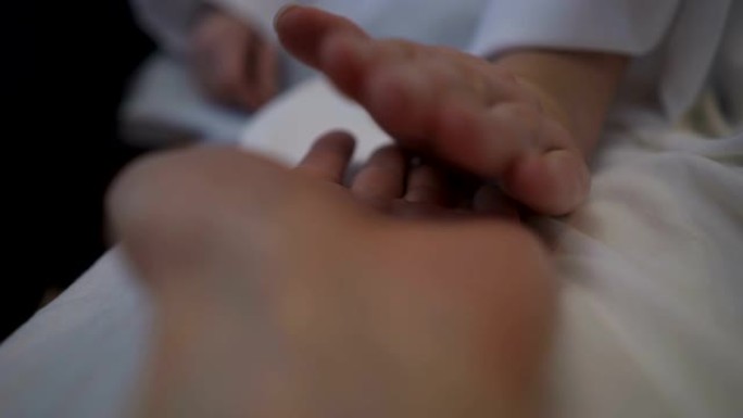 一个女人在医院里安抚一个男人，握着他的手