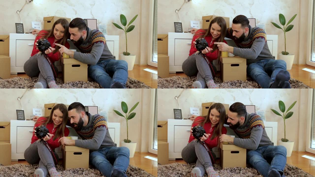 年轻夫妇坐在新家的地板上看着相机上的照片